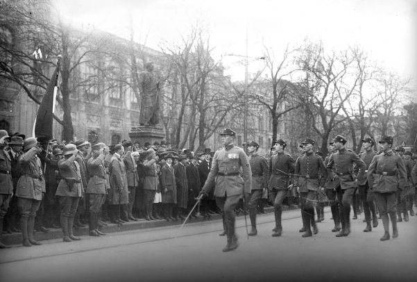 The SA marches to the War Memorial in Munich in 1923. A hatless Hitler reviews the parade from the pavement.