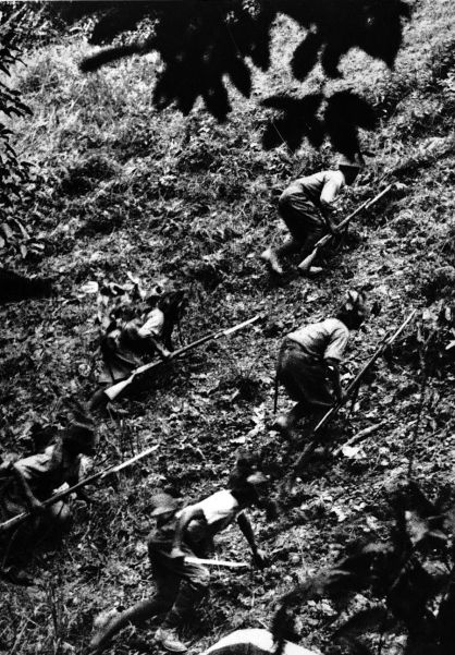 Japanese troops cautiously scale a hill during their advance to Singapore