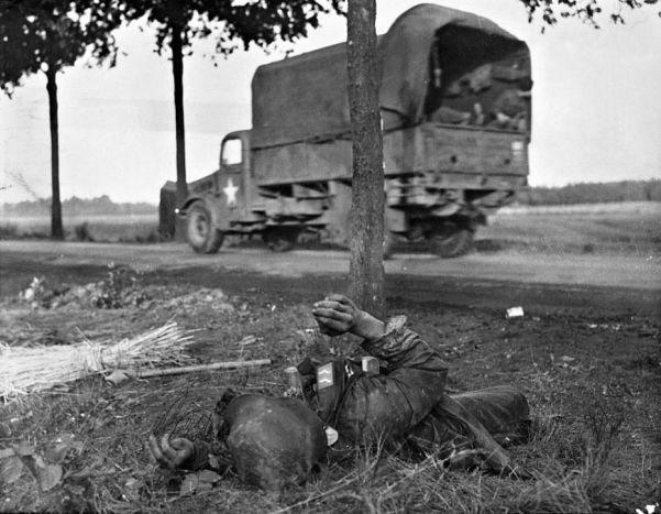 A US truck races past the corpse of a German soldier during the Allied drive to liberate Holland